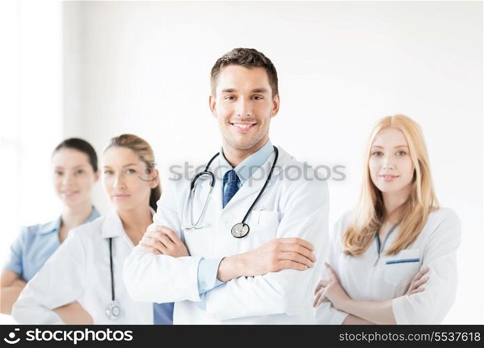 healthcare and medicine concept - attractive male doctor in front of medical group