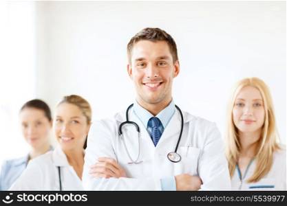 healthcare and medicine concept - attractive male doctor in front of medical group in hospital