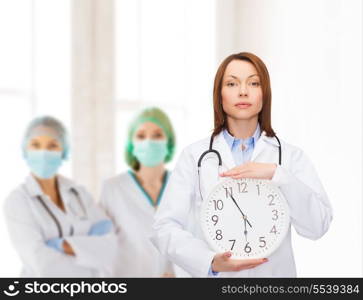 healthcare and medicine concept - calm female doctor with wall clock and stethoscope