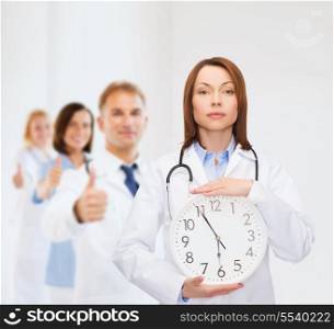 healthcare and medicine concept - calm female doctor with wall clock and stethoscope