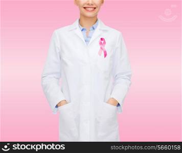 healthcare and medicine concept - close up of smiling female doctor with pink cancer awareness ribbon over pink background