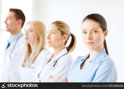 healthcare and medicine concept - female doctor or nurse in front of medical group in hospital
