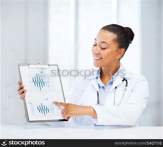 healthcare and medicine concept - female doctor with stethoscope pointing to cardiogram