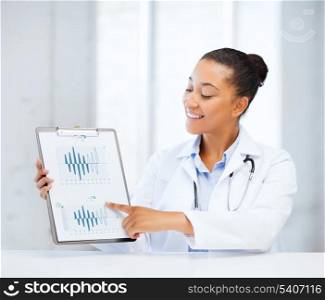 healthcare and medicine concept - female doctor with stethoscope pointing to cardiogram