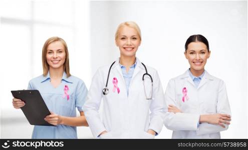 healthcare and medicine concept - female doctors with pink breast cancer awareness ribbon
