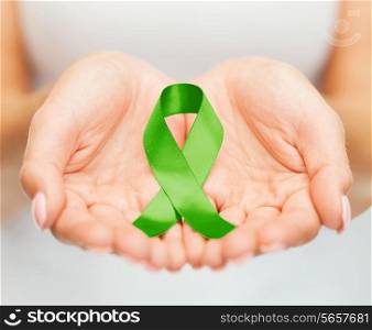 healthcare and medicine concept - female hands holding green organ transplant awareness ribbon