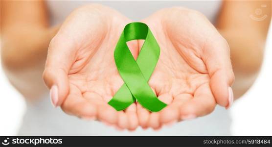 healthcare and medicine concept - female hands holding green organ transplant awareness ribbon. hands holding green awareness ribbon