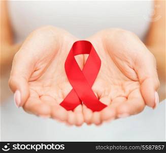 healthcare and medicine concept - female hands holding red AIDS awareness ribbon