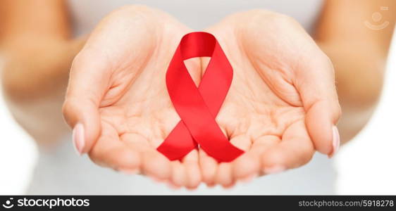 healthcare and medicine concept - female hands holding red AIDS awareness ribbon. hands holding red AIDS awareness ribbon