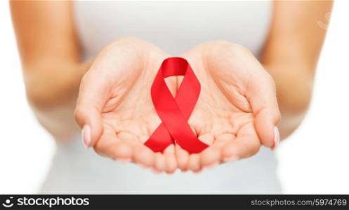 healthcare and medicine concept - female hands holding red AIDS awareness ribbon. hands holding red AIDS awareness ribbon