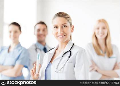 healthcare and medicine concept - group of medics with female doctor holding syringe with injection