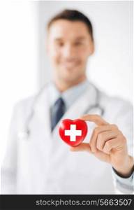 healthcare and medicine concept - male doctor holding heart with red cross symbol