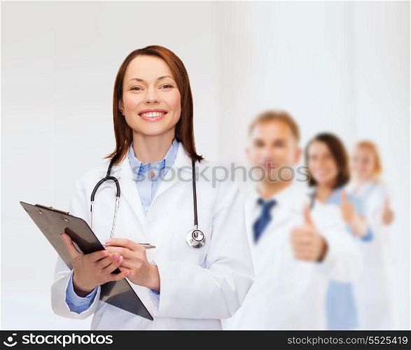 healthcare and medicine concept - smiling female doctor with clipboard and stethoscope