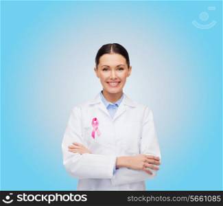 healthcare and medicine concept - smiling female doctor with pink cancer awareness ribbon over blue background