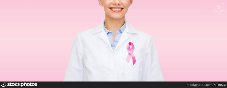 healthcare and medicine concept - smiling female doctor with pink cancer awareness ribbon over pink background. smiling female doctor with cancer awareness ribbon