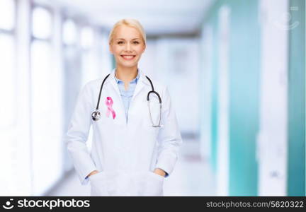 healthcare and medicine concept - smiling female doctor with stethoscope and pink cancer awareness ribbon over hospital background