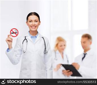 healthcare and medicine concept - smiling female doctor with stethoscope holding no smoking sign