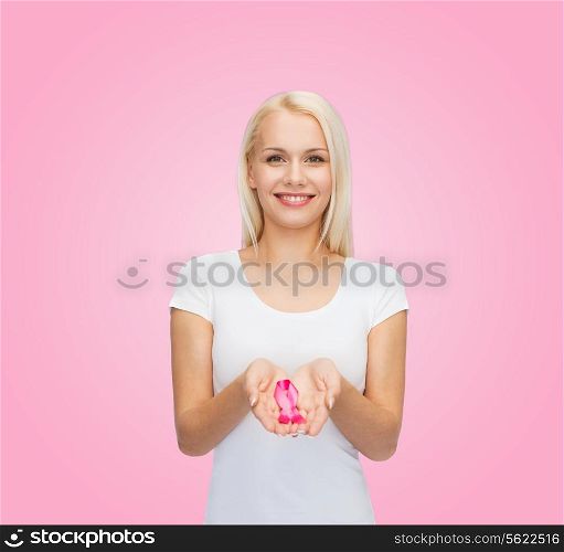 healthcare and medicine concept - smiling woman in blank t-shirt holding pink breast cancer awareness ribbon