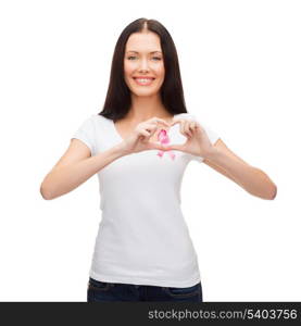 healthcare and medicine concept - smiling woman in blank white t-shirt with pink breast cancer awareness ribbon showing heart shape