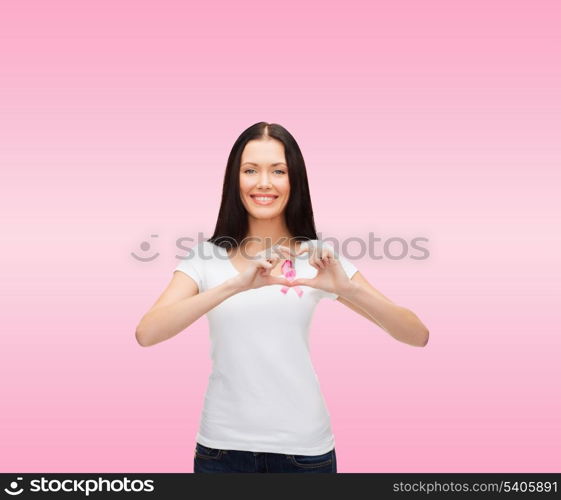 healthcare and medicine concept - smiling woman in blank white t-shirt with pink breast cancer awareness ribbon showing heart shape