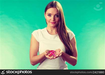Healthcare and medicine concept - woman showing pink breast cancer awareness ribbon on hands, against green teal. Woman with breast cancer awareness ribbon on hands
