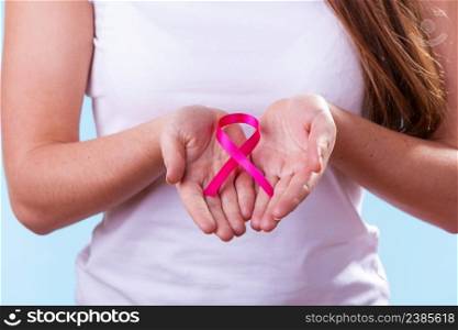 Healthcare and medicine concept - woman showing pink breast cancer awareness ribbon on hands, closeup. Woman with breast cancer awareness ribbon on hands