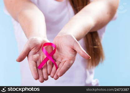 Healthcare and medicine concept - woman showing pink breast cancer awareness ribbon on hands, closeup. Woman with breast cancer awareness ribbon on hands