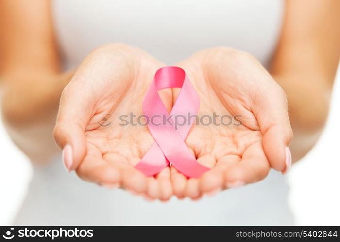 healthcare and medicine concept - womans hands holding pink breast cancer awareness ribbon