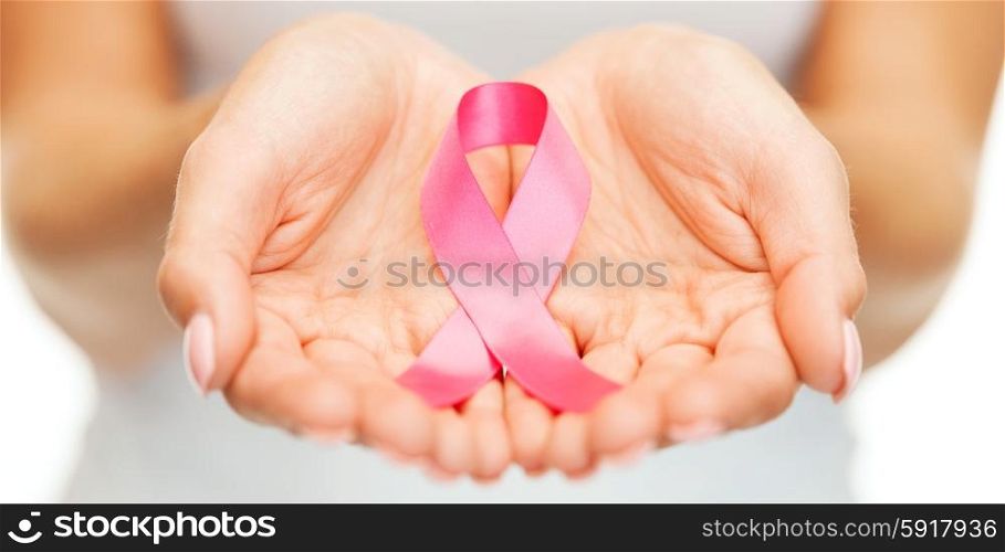 healthcare and medicine concept - womans hands holding pink breast cancer awareness ribbon. hands holding pink breast cancer awareness ribbon