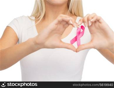 healthcare and medicine concept - young woman in blank white t-shirt with pink breast cancer awareness ribbon showing heart shape