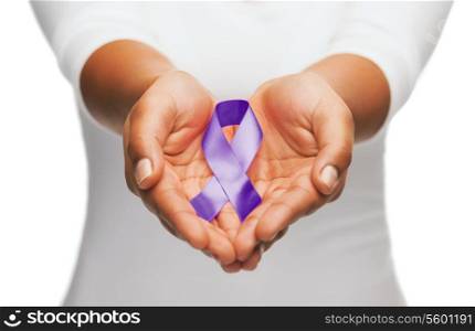 healthcare and social problem concept - womans hands holding purple domestic violence awareness ribbon