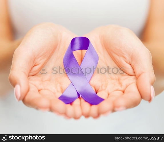 healthcare and social problems concept - womans hands holding purple domestic violence awareness ribbon
