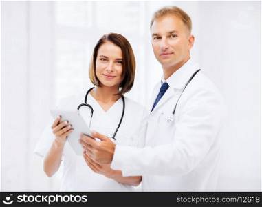healthcare and technology concept - two doctors looking at tablet pc