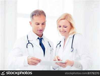 healthcare and technology concept - two doctors looking at tablet pc. two doctors looking at tablet pc