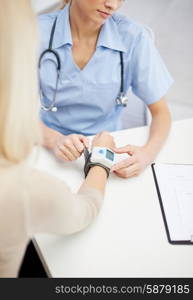 healthcare, cardiology, people and medicine concept - close up of female doctor with wrist tonometer measuring blood pressure or pulse rate to patient