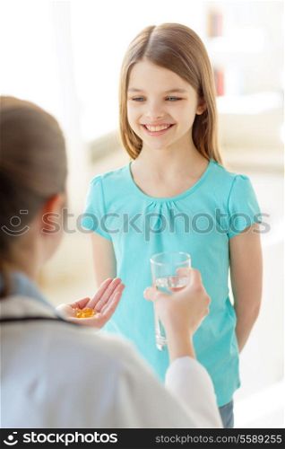 healthcare, child and medical concept - female doctor giving pills and water to little girl in hospital
