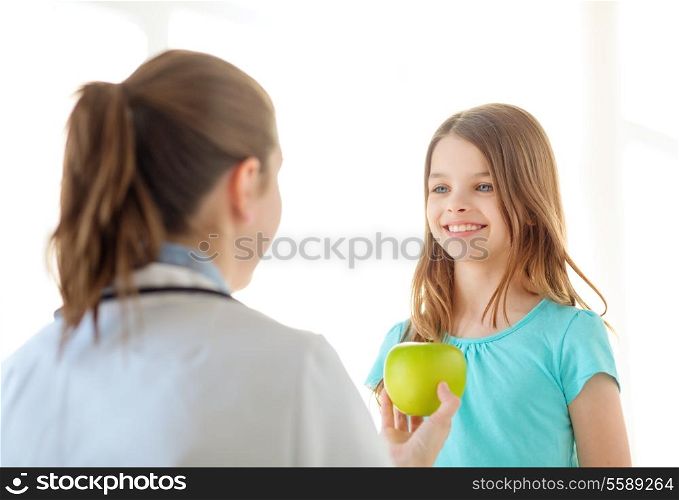 healthcare, child and medicine concept - female doctor giving an apple to smiling little girl