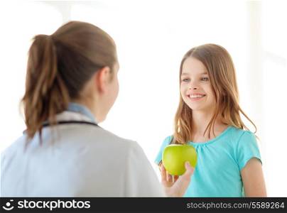 healthcare, child and medicine concept - female doctor giving an apple to smiling little girl
