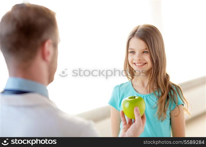 healthcare, child and medicine concept - male doctor giving an apple to smiling little girl