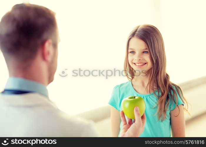 healthcare, child and medicine concept - male doctor giving an apple to smiling little girl