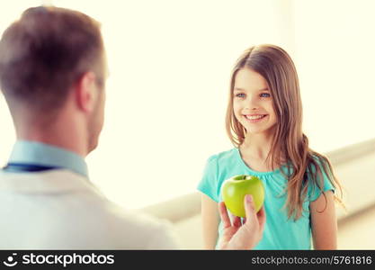 healthcare, child and medicine concept - male doctor giving an apple to smiling little girl