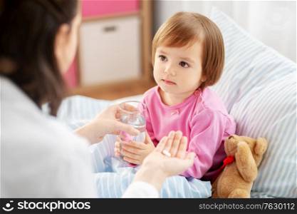 healthcare, children and people concept - doctor giving medicine to little sick african american girl in bed at home. doctor giving medicine to sick girl in bed at home