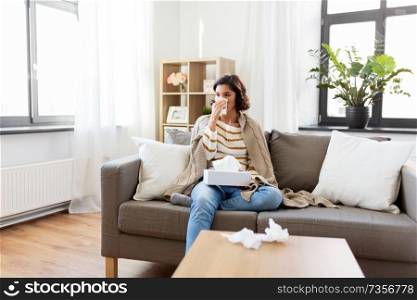 healthcare, cold, hygiene and people concept - sick woman blowing her runny nose in paper tissue at home. sick woman blowing nose in paper tissue at home