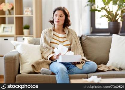 healthcare, cold, hygiene and people concept - sick woman in blanket taking paper tissue from box at home. sick woman taking paper tissue from box at home
