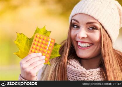 Healthcare concept. Beauty positive smiling woman with tablets pills and big gold leaf in autumnal park. Cold and illness.. Woman with pills outdoor