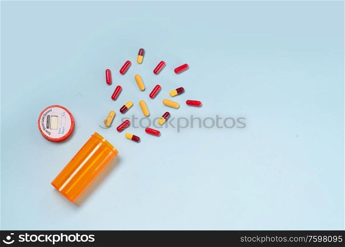Healthcare concept - orange bottle with scattered pills on blue background with copy space. Healthcare concept on blue