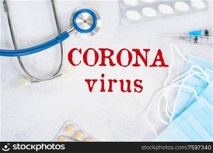 Healthcare concept - stethoscope, masks and white pills on blue , corona virus words on the table. Healthcare concept on blue