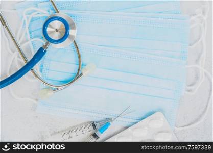 Healthcare concept - stethoscope, masks and white pills on white table, corona virus concept. Healthcare concept on blue