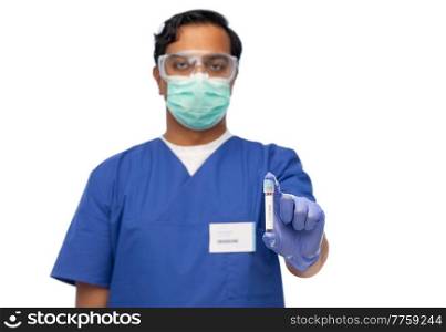 healthcare, coronavirus and medicine concept - doctor in blue uniform, face protective medical mask for protection from virus disease, goggles and gloves with blood in test tube over white background. male doctor in mask with blood in test tube