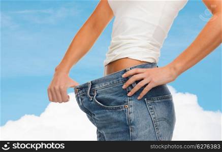 healthcare, diet and fitness concept - close up of female showing big jeans
